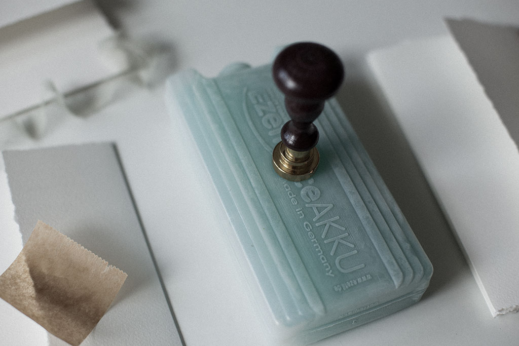 Sealing a wedding invitation with silk ribbon and a way seal.