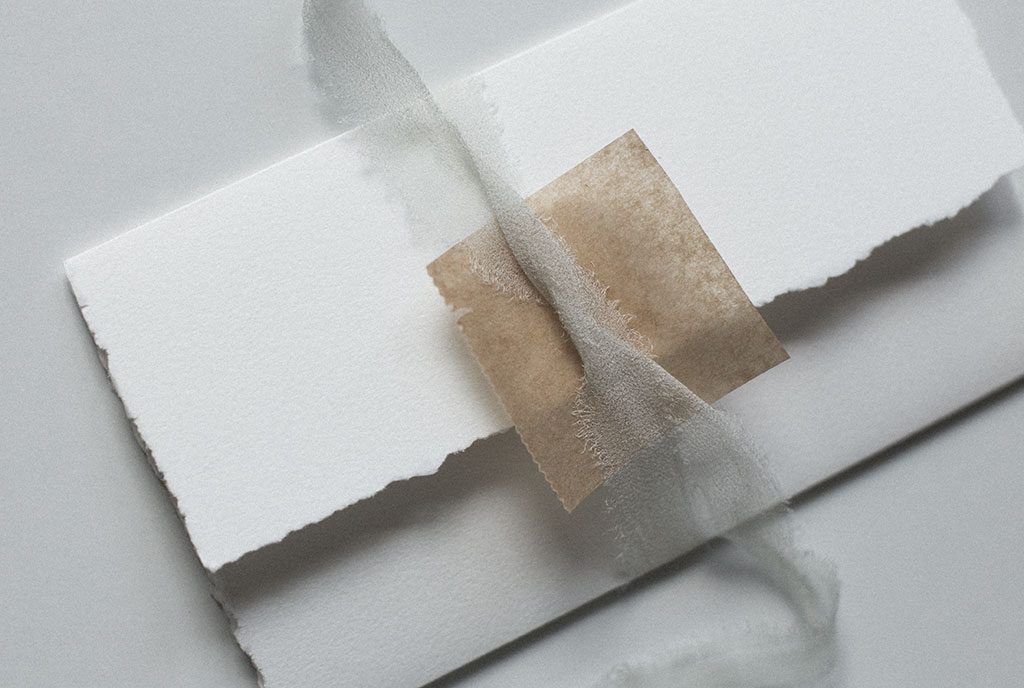 Sealing a wedding invitation with silk ribbon and a wax seal.